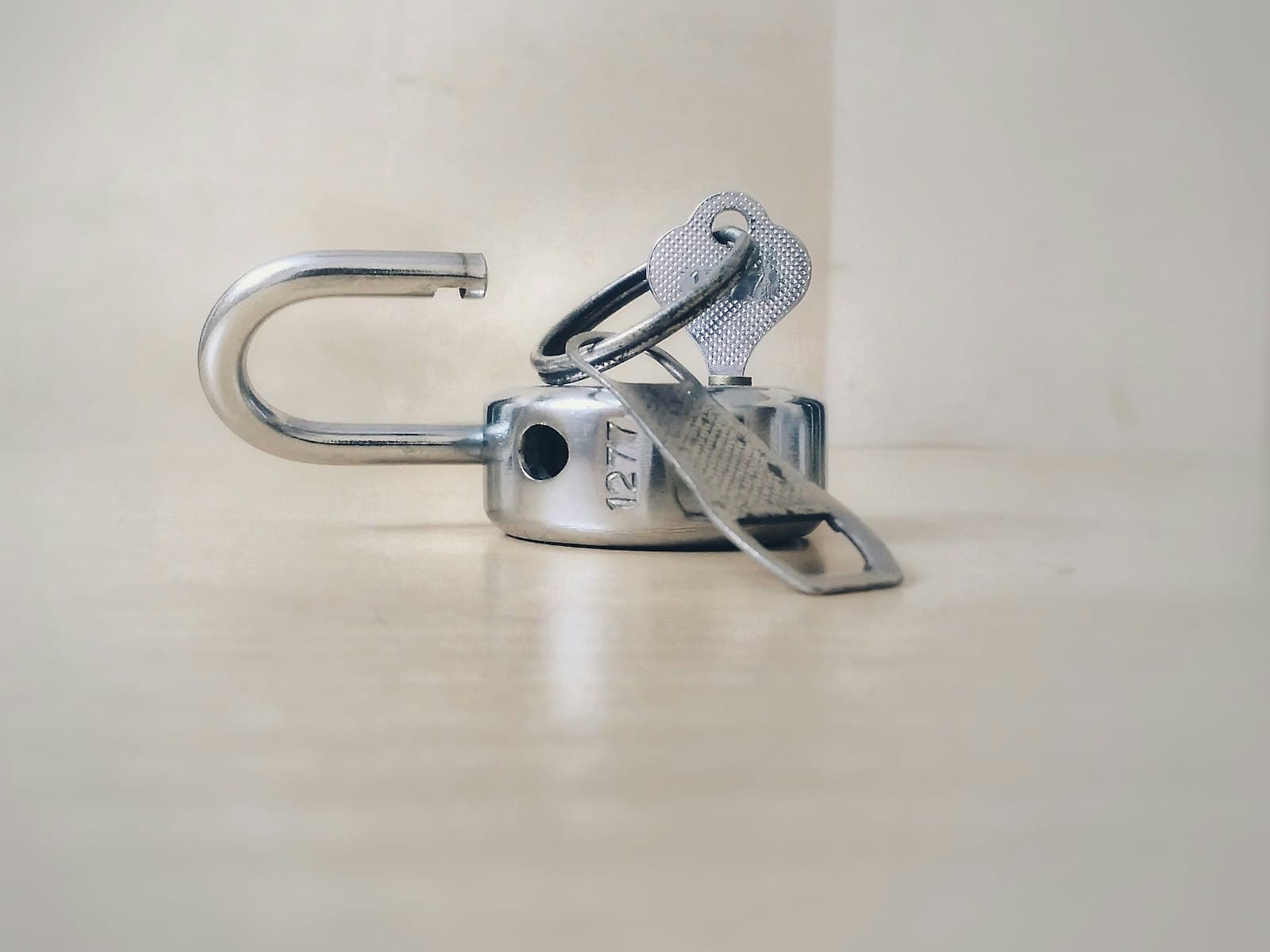 Open steel padlock lying on a light surface